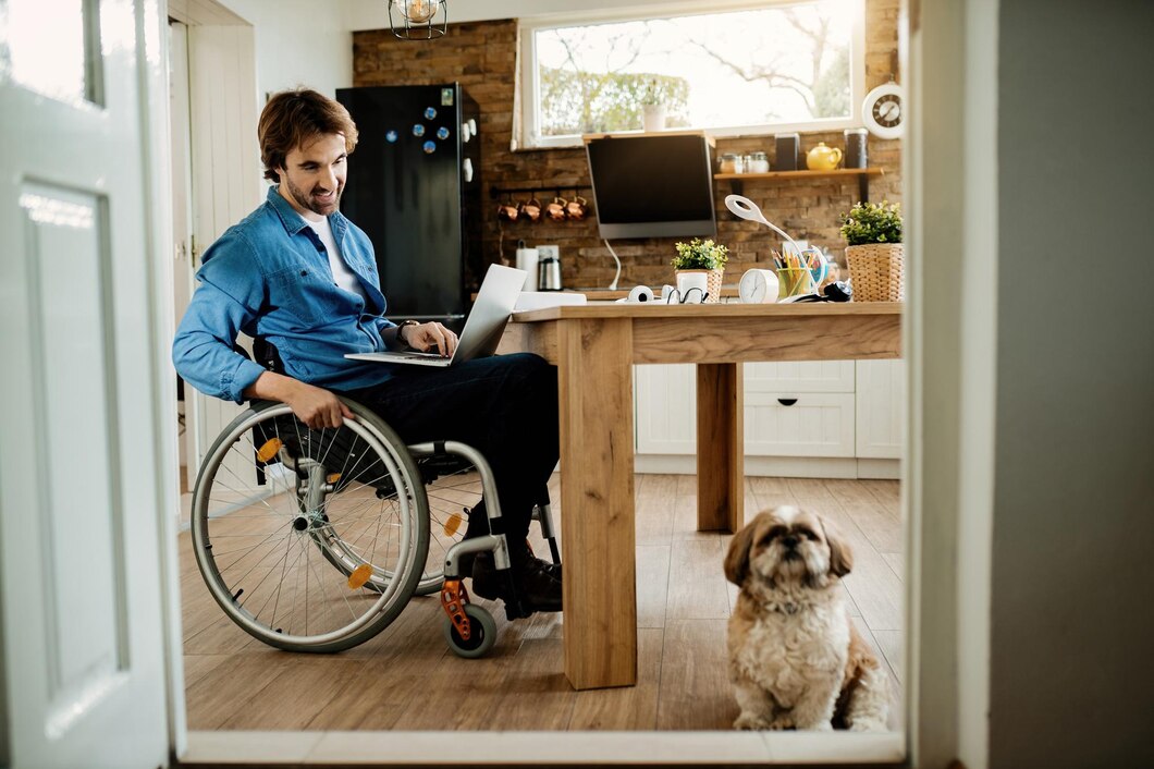 happy-businessman-wheelchair-looking-his-dog-while-working-laptop-home_637285-3026