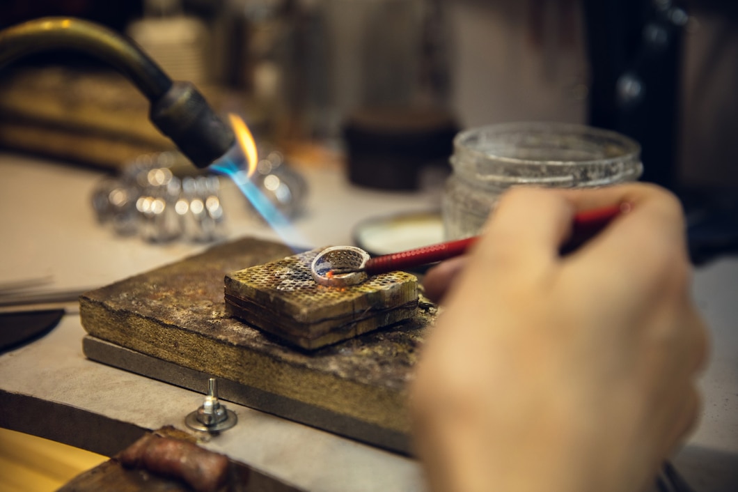 close-up-hands-jeweller-goldsmiths-making-golden-ring-with-gemstone-using-professional-tools_155003-26352